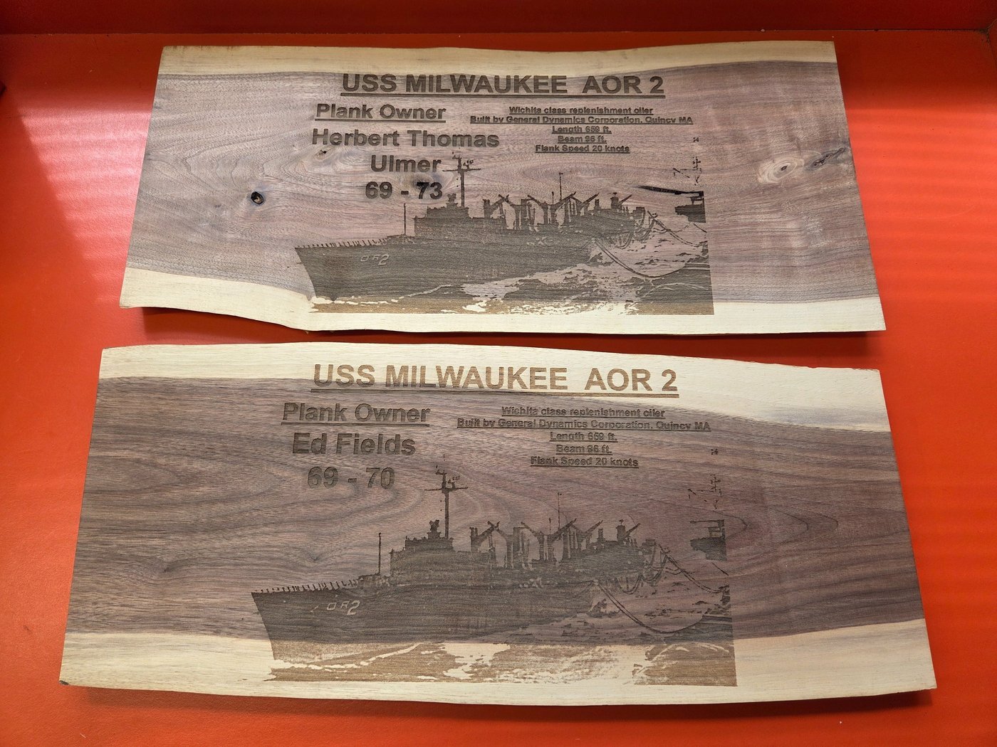 Two live-edge walnut plaques engraved with the USS Milwaukee AOR 2, its plank owners' names and their service years.