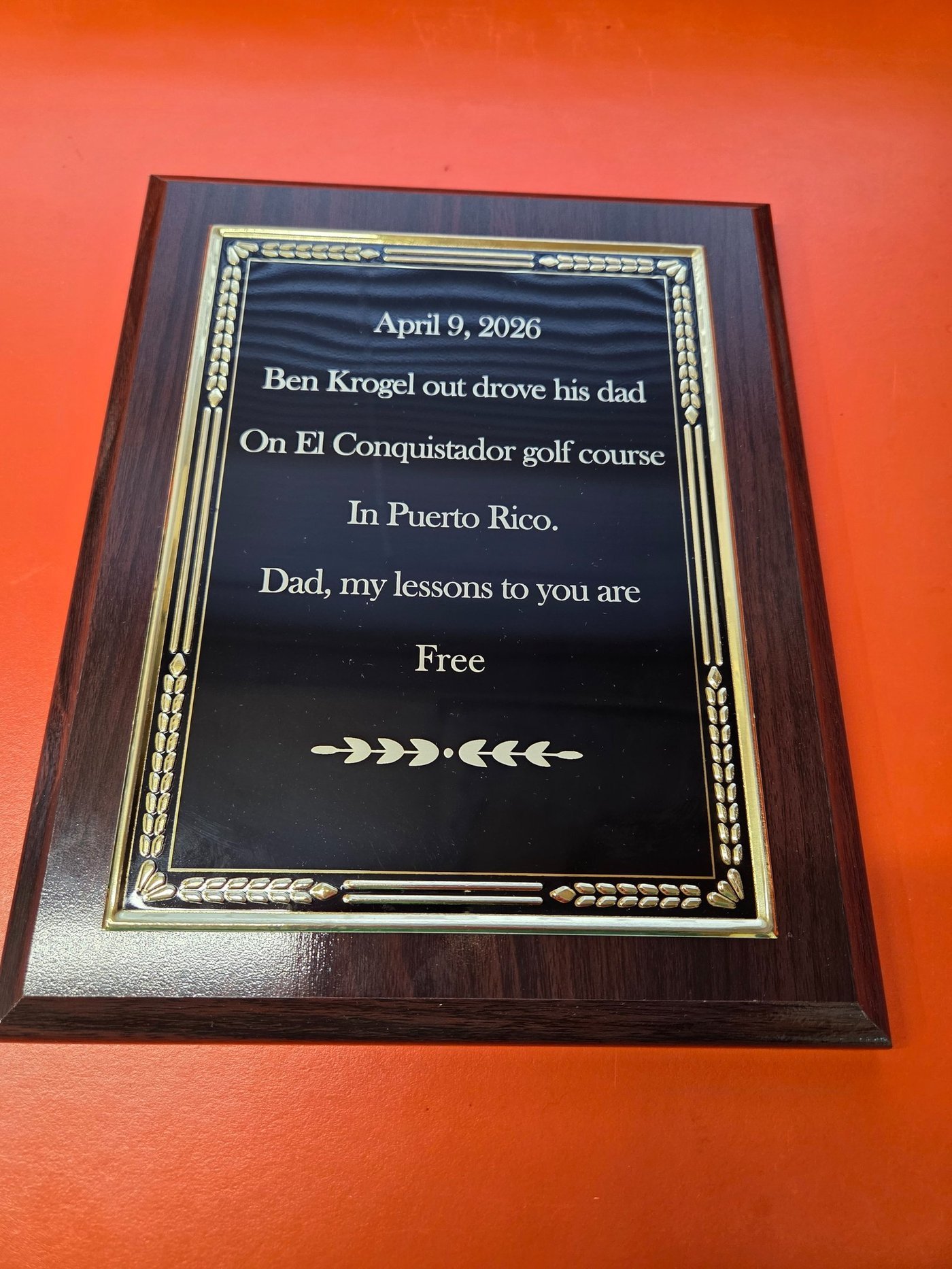 A black and gold plaque mounted on wood, engraved with a humorous tribute about a golf round in Puerto Rico.
