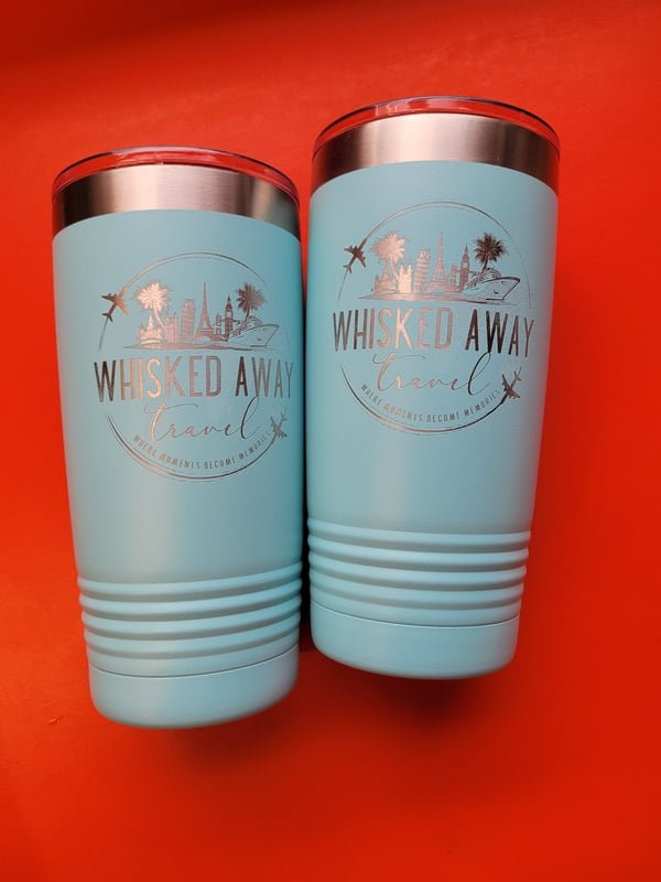 Two seafoam-green insulated tumblers engraved with the Whisked Away Travel logo showing landmarks, a plane and a cruise ship.