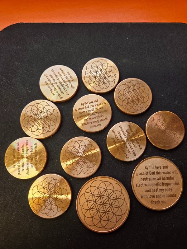 Eleven brass and copper discs fiber-engraved with a Flower of Life pattern on one face and a blessing inscription on the other.