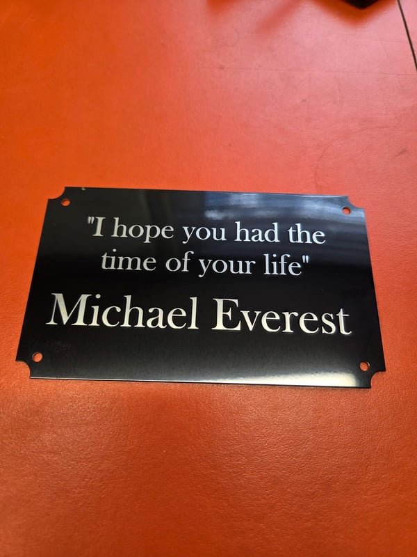 A black metal plaque engraved in white with the words I hope you had the time of your life, Michael Everest.