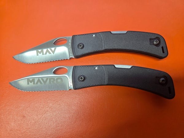 Two folding knife blades fiber-engraved with the names MAV and MAVRO.