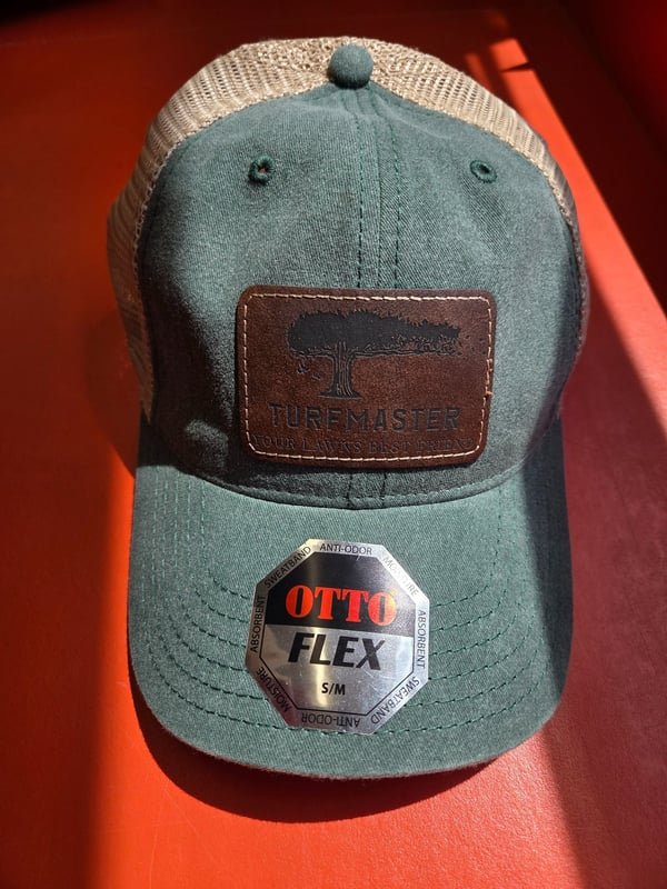 A green cap with a leather patch engraved with the TurfMaster tree logo.