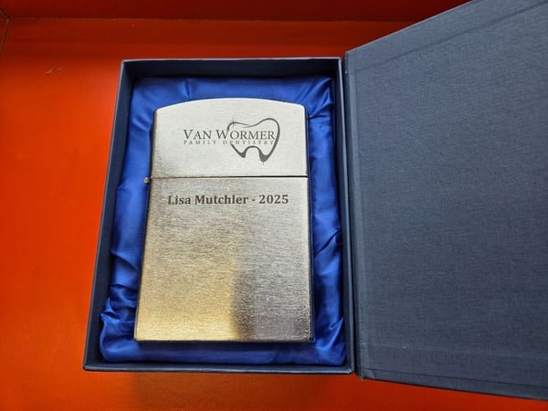 A brushed metal lighter in a presentation box, engraved with the Van Wormer Family Dentistry logo and Lisa Mutchler 2025.