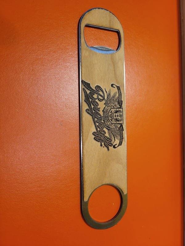 A slim wooden bottle opener engraved with an eagle crest.