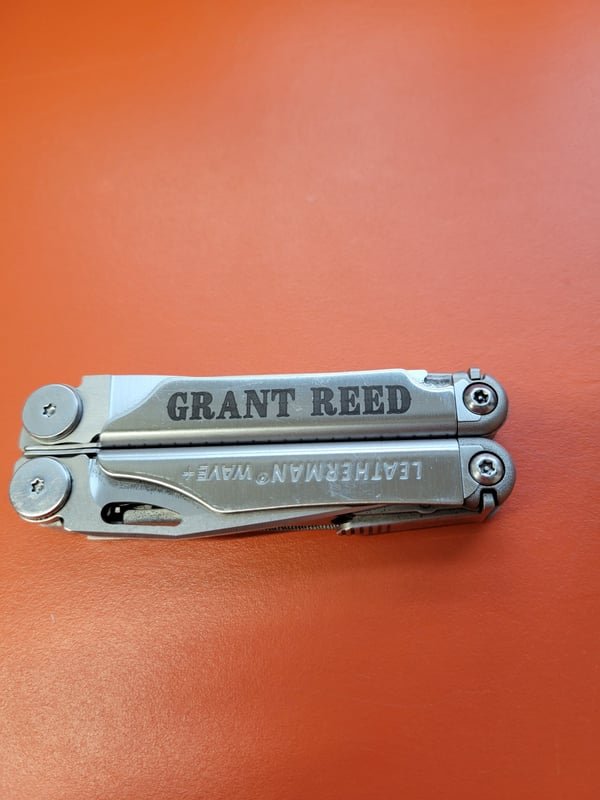 A Leatherman multitool fiber-engraved with the name Grant Reed along its handle.