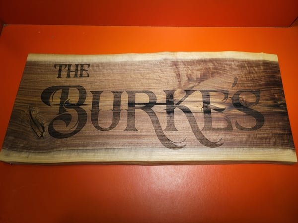 A live-edge wood sign engraved in large decorative letters reading The Burke's.