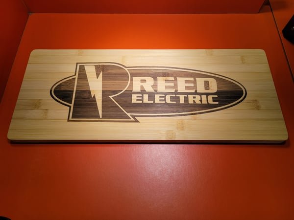 A bamboo sign engraved with the Reed Electric lightning-bolt logo.