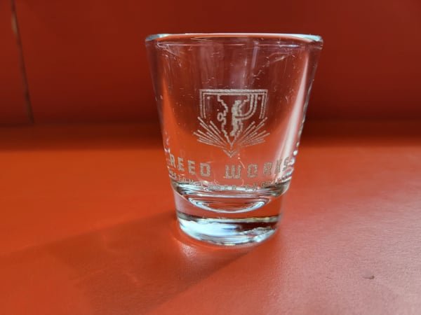 A shot glass etched with the Reed Works logo.