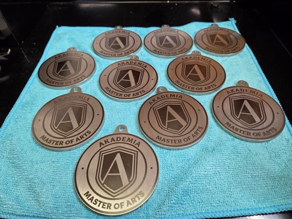 A group of round leather medallions engraved with the Akademia Master of Arts shield.