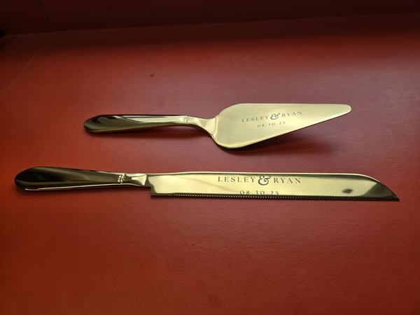 A gold cake knife and server set fiber-engraved with the names Lesley and Ryan and their wedding date.