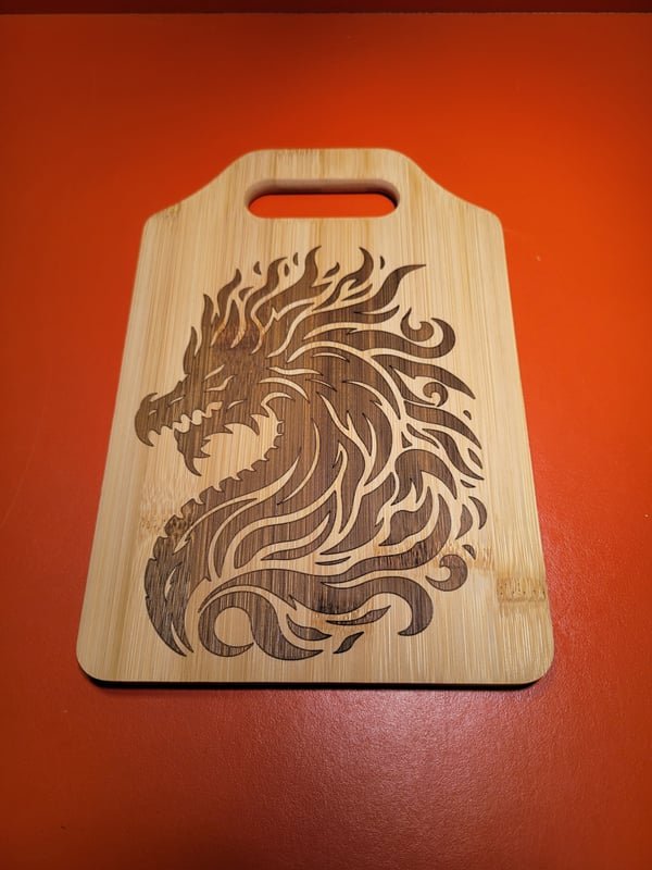 A bamboo cutting board engraved with a flowing dragon design.