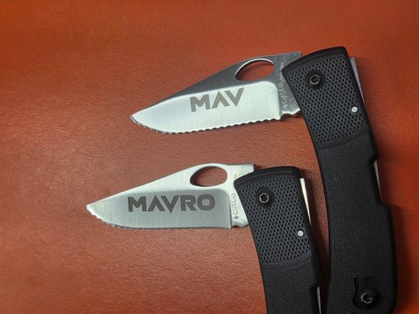 Two knife blades fiber-engraved with the names MAV and MAVRO.