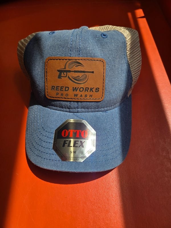 A denim cap with a leather patch engraved with the Reed Works Pro Wash pressure-washer logo.