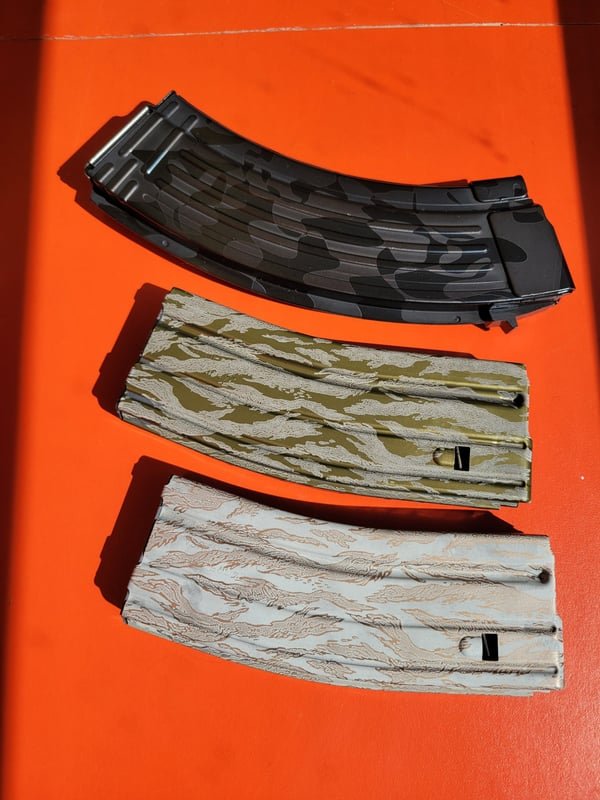 Three rifle magazines in black, tan and grey camouflage patterns, each fiber-engraved.