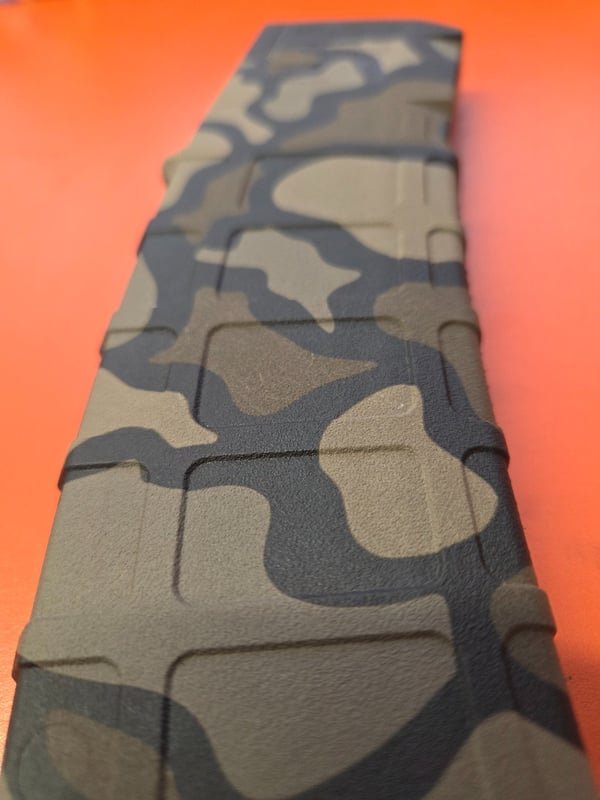A close-up of a camouflage rifle magazine showing the crispness of the fiber-engraved marks.