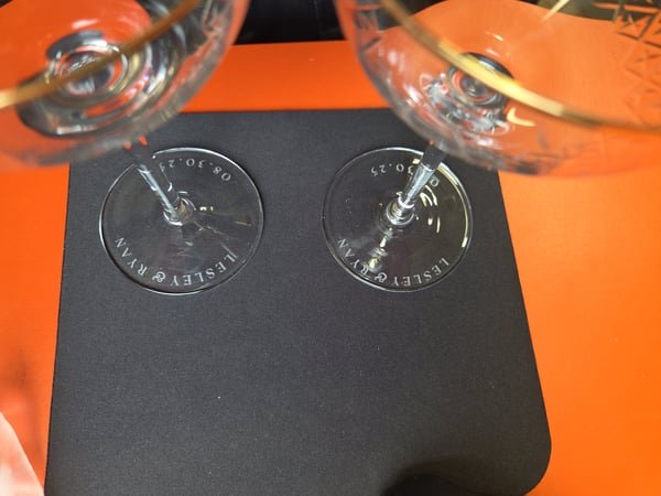 Two wine glasses etched at the base with the names Lesley and Ryan and their wedding date.