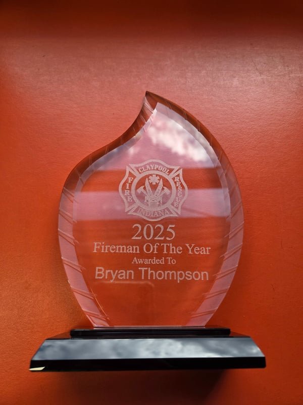 A clear acrylic flame-shaped award engraved 2025 Fireman Of The Year, awarded to Bryan Thompson.