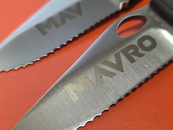 A close-up of two knife blades showing the fine detail of the fiber-engraved names.