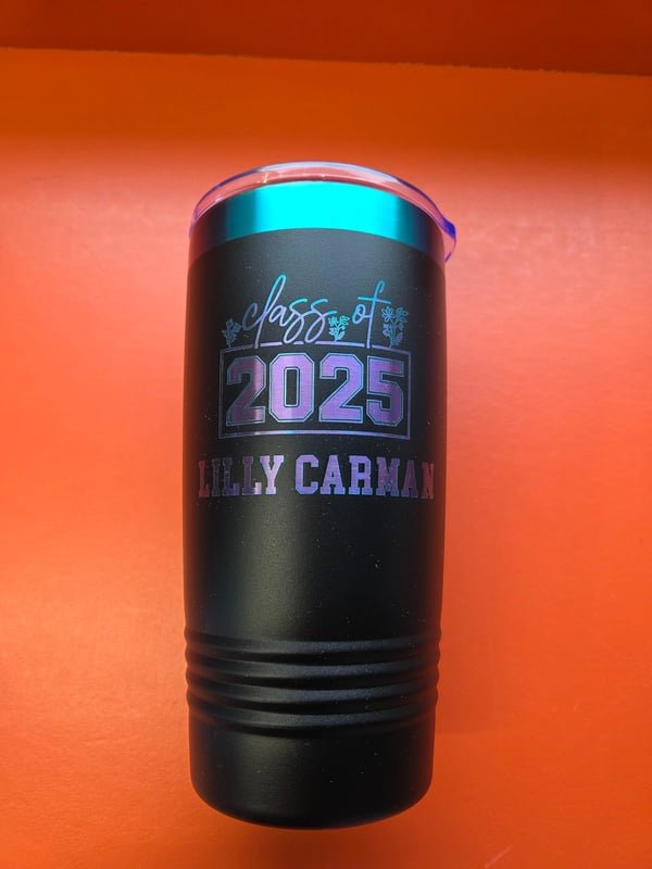 A black tumbler engraved Class of 2025, Lilly Carman, the marks shifting through blue and violet.