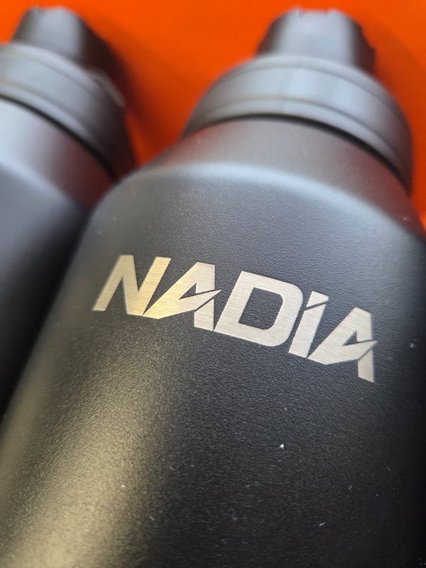 A dark grey bottle engraved with the name Nadia in colour-shifted marks.