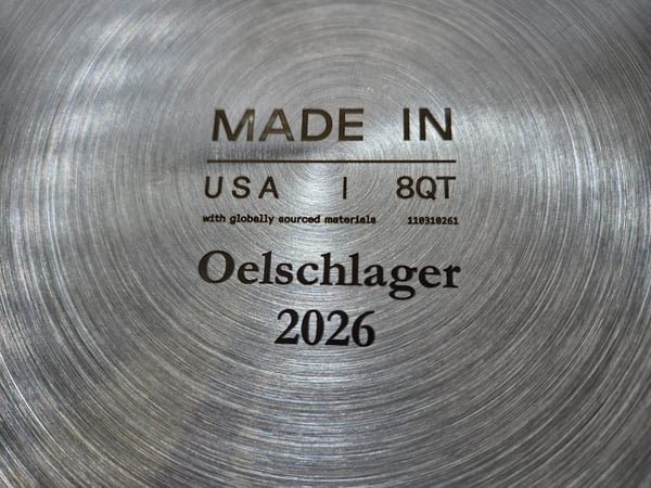 The base of a stainless pan fiber-engraved Made in USA, 8QT, Oelschlager 2026.
