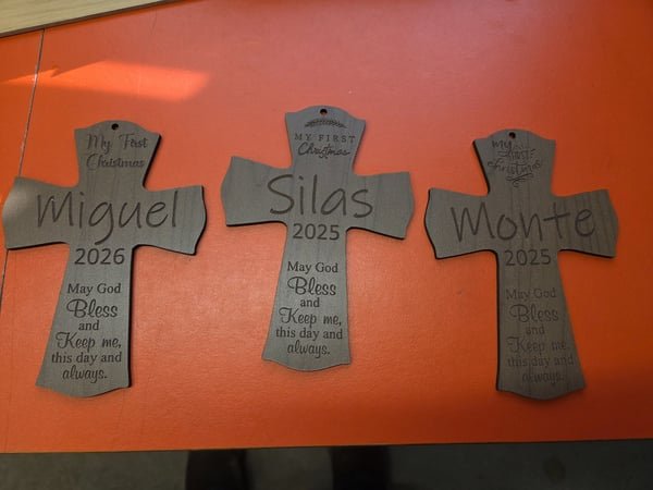 Three wooden crosses engraved with the names Miguel, Silas and Monte and a My First Christmas blessing.