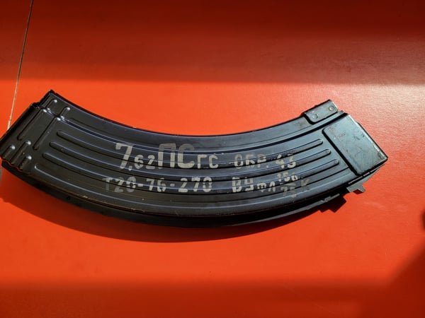 A rifle magazine fiber-engraved with calibre markings and a serial number.