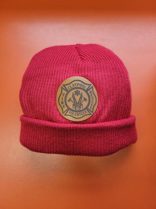 A pink knit beanie with a round leather patch engraved with the Claypool Fire Rescue crest.