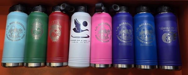 Four insulated bottles in red, white, pink and blue, engraved with lake life and conservation camp logos.