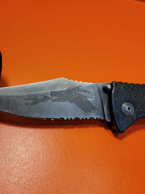 A folding knife with its blade fiber-engraved in a flowing pattern.