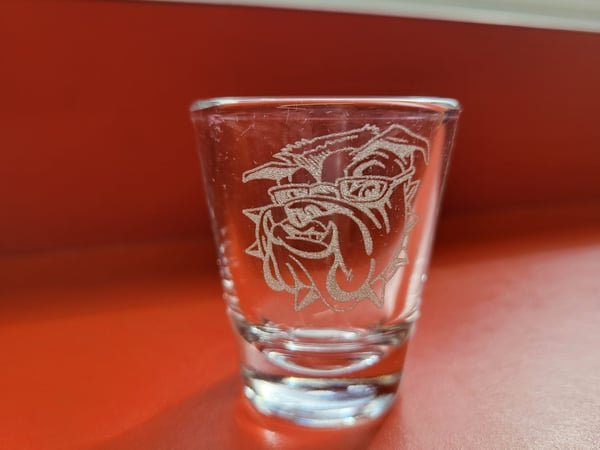 A shot glass etched with a bulldog mascot.