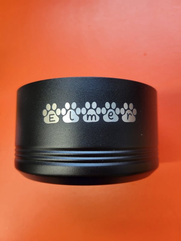 The base of a black tumbler engraved with the name Elmer spelled out between paw prints.