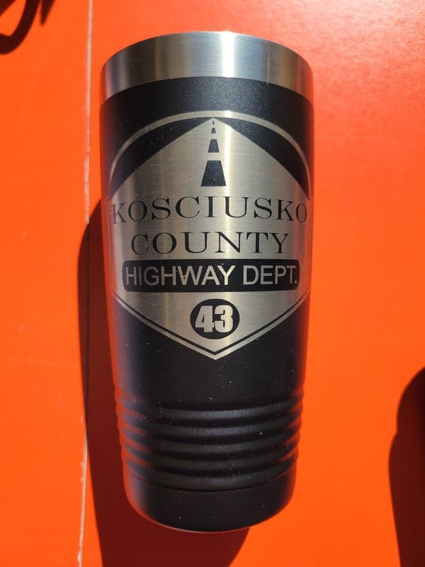 A black tumbler engraved with the Kosciusko County Highway Department crest and the number 43.