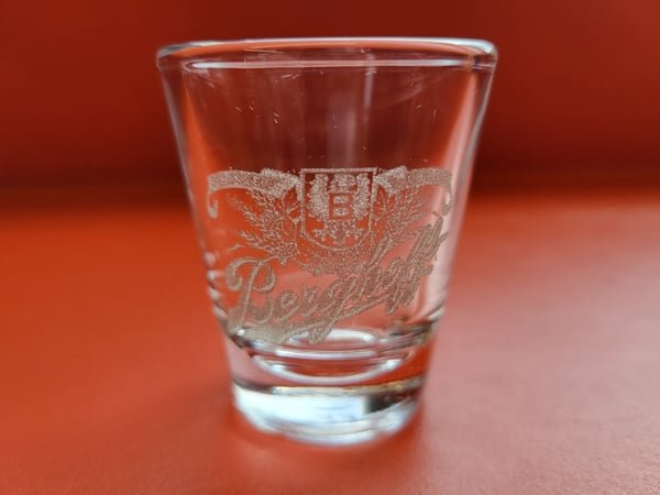 A shot glass etched with a tiger crest.