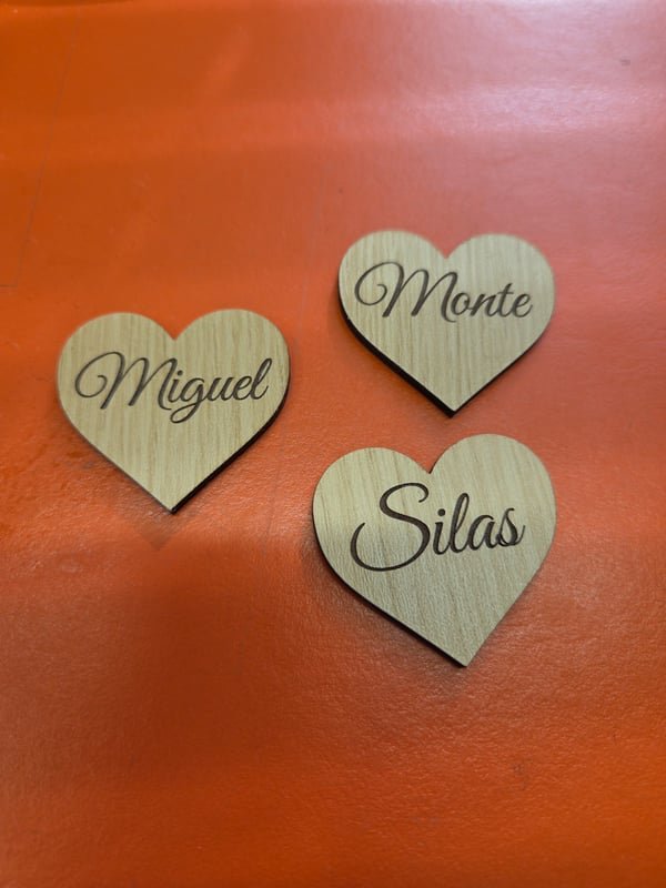 Three small wooden hearts engraved in script with the names Miguel, Monte and Silas.