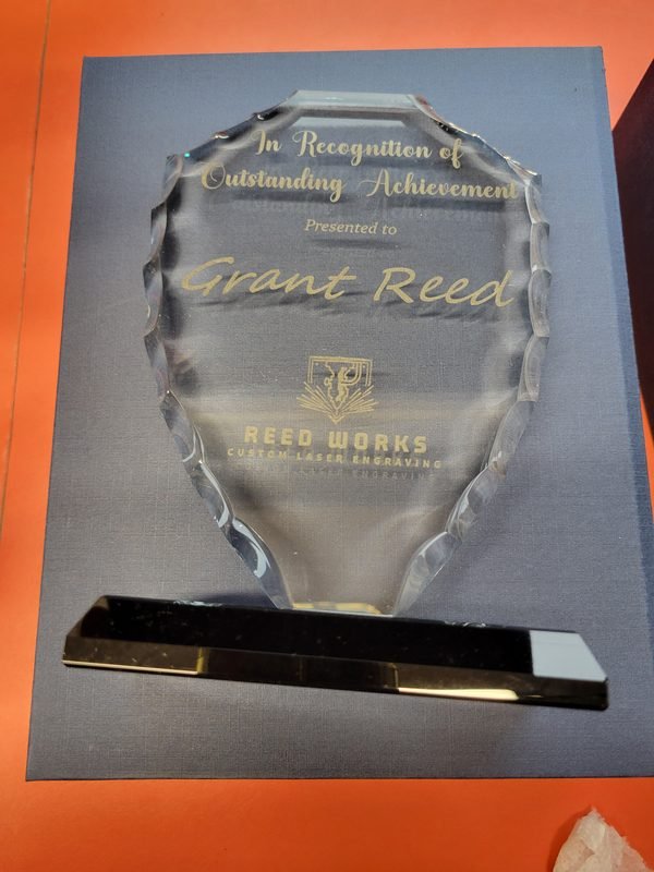 A faceted glass award engraved In Recognition of Outstanding Achievement, presented to Grant Reed.
