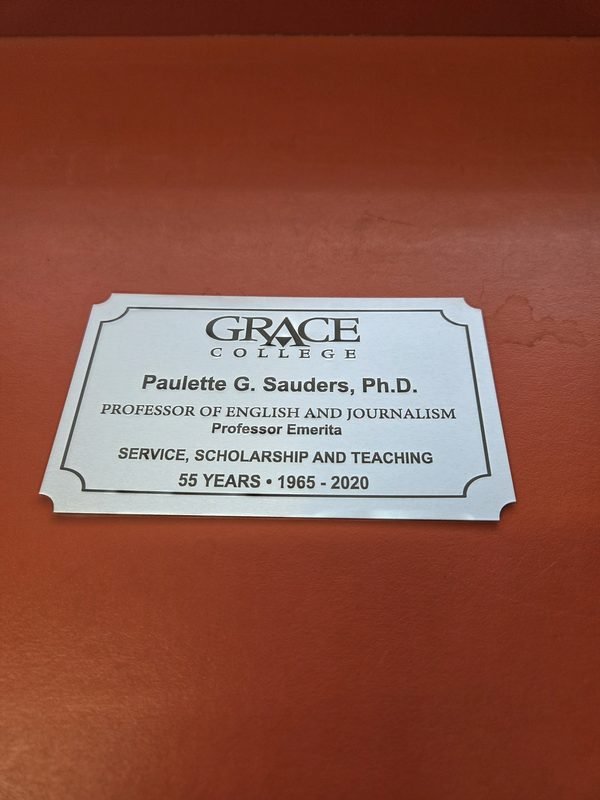 A brushed metal plaque engraved for Paulette G. Sauders, Ph.D., Professor of English and Journalism at Grace College.