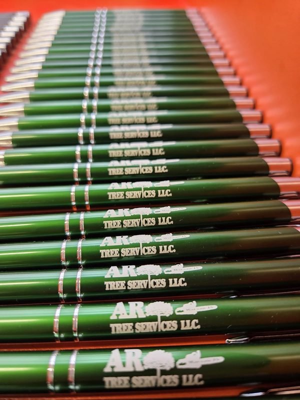 Rows of green metal pens engraved with the AR Tree Services LLC logo.
