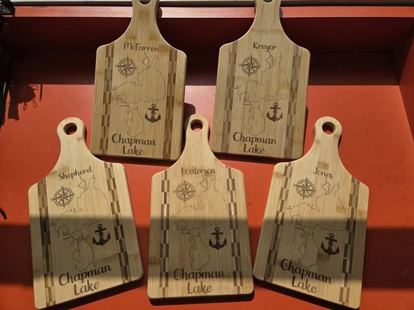 Five bamboo paddle boards engraved with a Chapman Lake map, a compass rose, an anchor and each family's name.