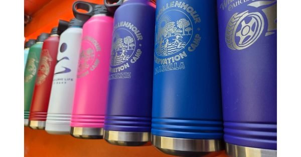 Insulated bottles in pink, white, red and blue, each engraved with a conservation camp or lake life logo.