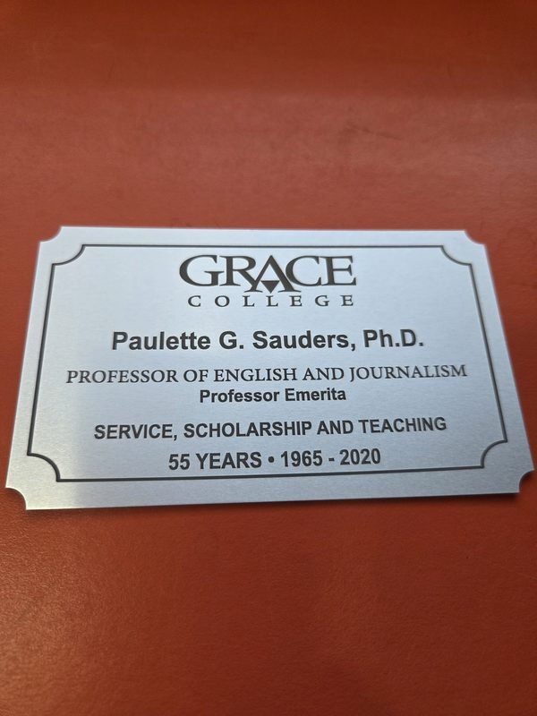 A brushed metal Grace College plaque honouring 55 years of service, scholarship and teaching.