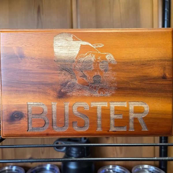 A cedar keepsake box engraved with a portrait of a dog splashing through water above the name Buster.