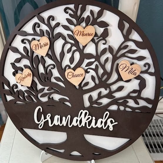 A cut wooden family tree hung with engraved name hearts above the word Grandkids.