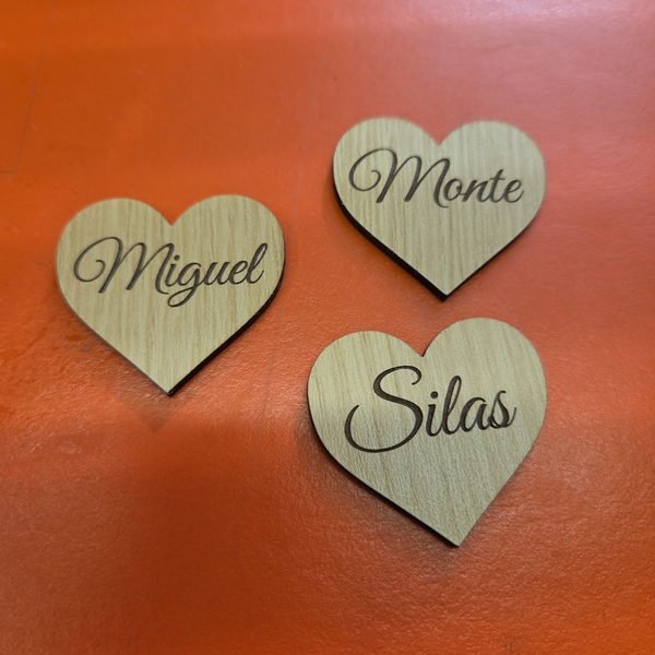 Three wooden hearts engraved in script with the names Miguel, Monte and Silas.