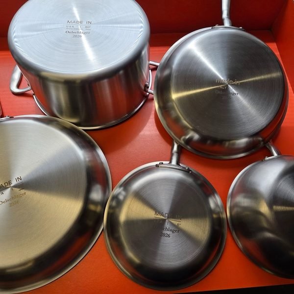 A boxed set of stainless steel pans, each base fiber-engraved with the family name and year.