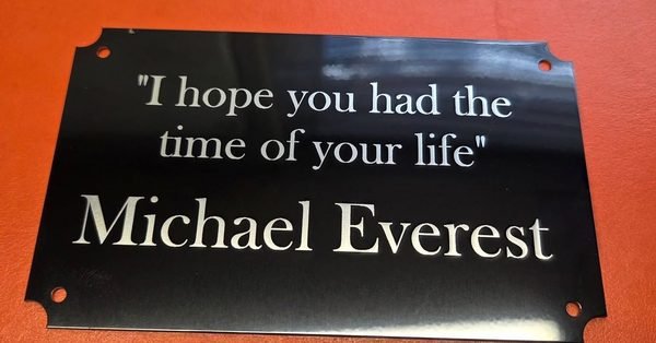 A black metal plaque engraved in white with the words I hope you had the time of your life, Michael Everest.