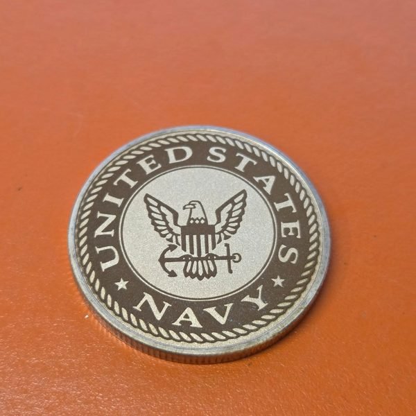 A challenge coin fiber-engraved with the United States Navy eagle and anchor crest.