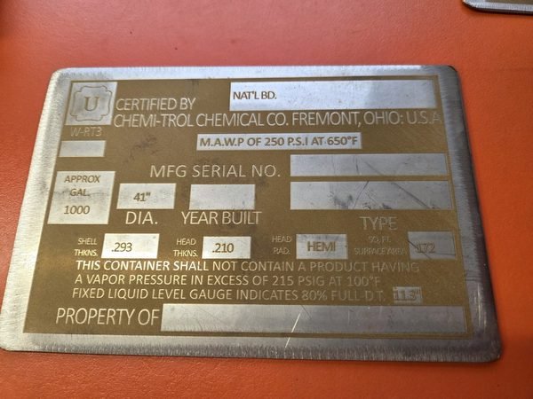 A brass pressure-vessel data plate engraved with certification details, serial number and build year.