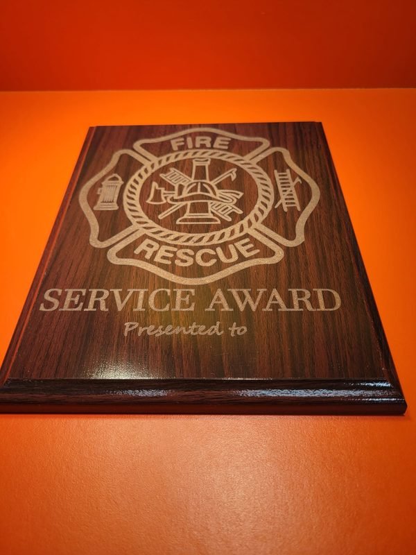 A wood-grain plaque engraved with a fire rescue maltese cross above the words Service Award, Presented to.